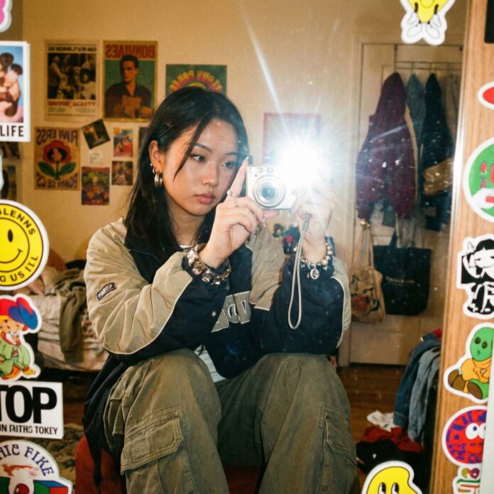 거울 앞에서 구형 빈티지 디카로 플래시를 터뜨려 셀카를 찍는 모습, Y2K 감성과 디카 열풍을 상징하는 이미지