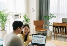 “나도 혜택 대상일까?” 2026 기준 중위소득 인상과 달라지는 복지 혜택 거실에서 정부의 2026 기준 중위소득 발표 뉴스를 보며 혜택을 확인하는 30대 한국인 부부