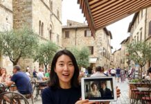 “영화 속 그곳으로 떠난다” 세트 제팅 여행 트렌드와 추천 명소 유명 드라마 촬영지인 아름다운 해변 카페에서 태블릿으로 관련 영상을 보며 여행을 즐기는 30대 한국인 여성