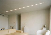 “아파트 반값으로 펜트하우스 감성을?” 실속파를 위한 빌라 인테리어 실전 견적 가이드 따뜻한 베이지 톤의 마이크로시멘트 바닥과 세련된 라인 조명이 설치된 감각적인 거실 인테리어